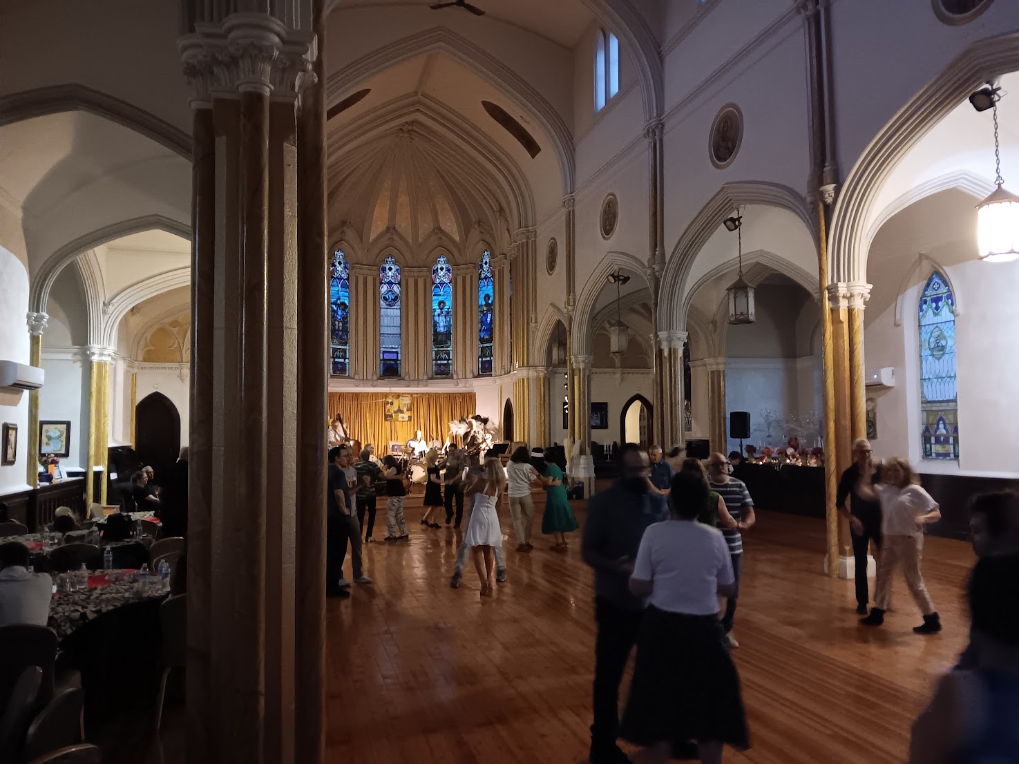 A social dance in a hall with a wooden floor and a band
